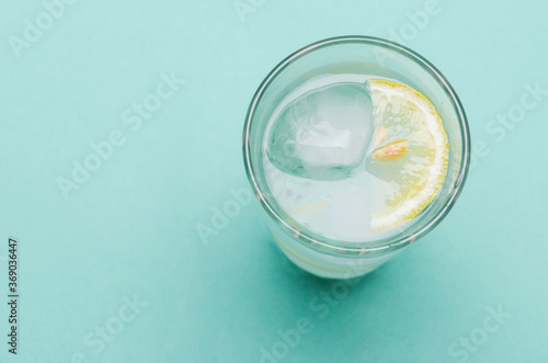 Cocktail with ice and lemon slice on blue background