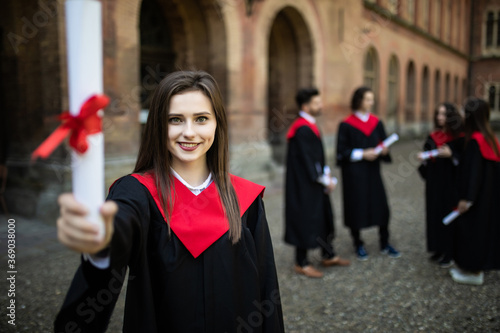 Friendly students in graduation gowns interacting with graduation girl in front