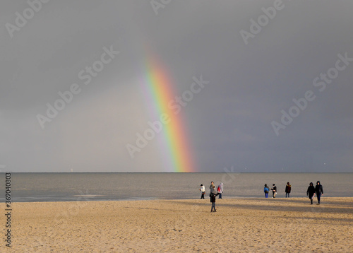 Rainbow over the beach in the North Sea. Rainy day, seagulls, rainbow, people. Nature miracle.