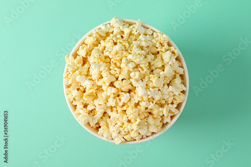 Cardboard bucket with tasty popcorn on mint background