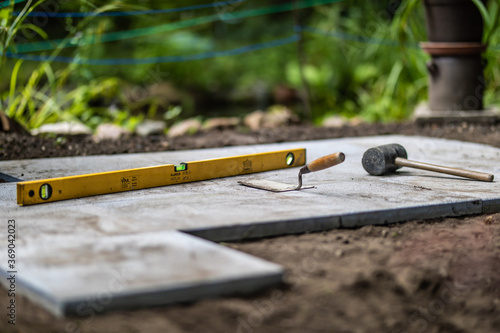 Gummihammer Kelle und Wasserwage mit Gehwegplatten beim verlegen im Garten