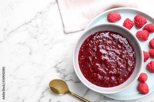 Delicious jam and fresh raspberries on white marble table, flat lay. Space for text