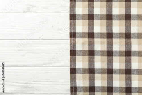 Checkered tablecloth on white wooden background, space for text