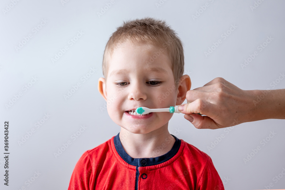 The toddler brushes his teeth with the help of a parent. Concept of learning a child dental care and hygiene The toddler brushes his teeth with the help of a parent. Concept of learning a child dental care and hygiene