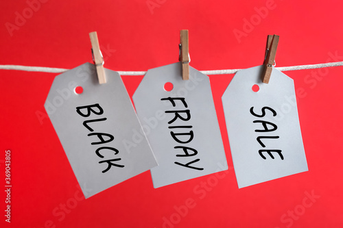 Blank tags hanging on red background. Black Friday concept