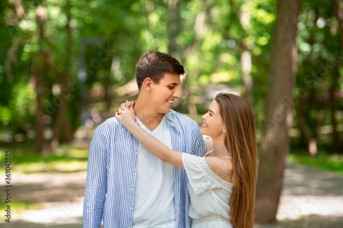 Attractive girl looking at her boyfriend with love and hugging him at park