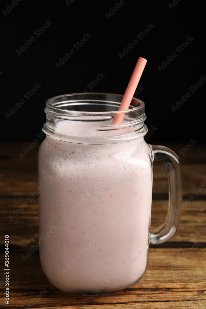 Tasty milk shake with straw in mason jar on wooden table Tasty milk shake with straw in mason jar on wooden table