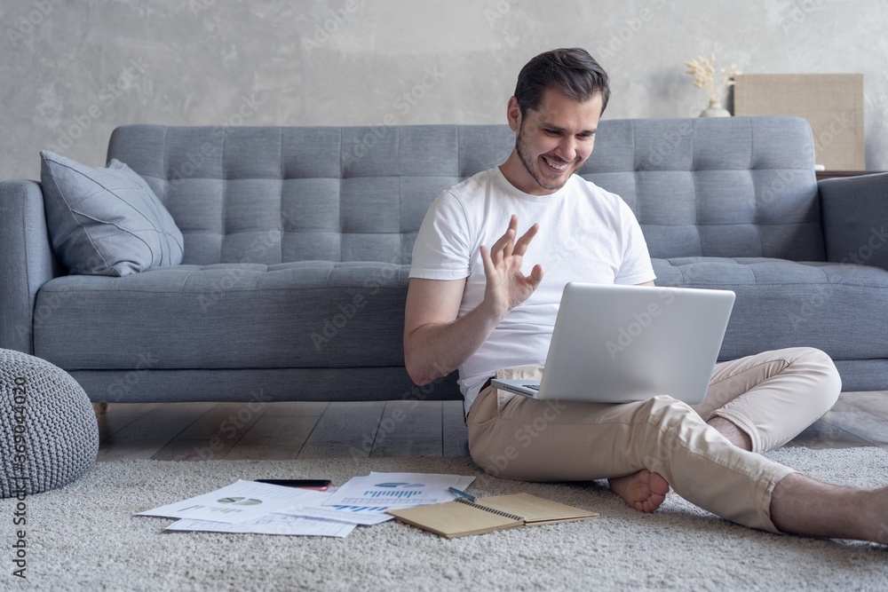 Man working on laptop computer sitting on the floor with his diary and official papers at home. Man working on laptop computer sitting on the floor with his diary and official papers at home.