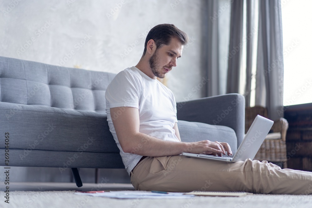 Man working on laptop computer sitting on the floor with his diary and official papers at home. Man working on laptop computer sitting on the floor with his diary and official papers at home.