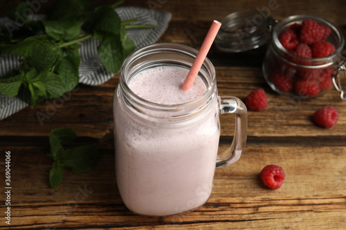 Tasty milk shake with raspberries and mint on wooden table