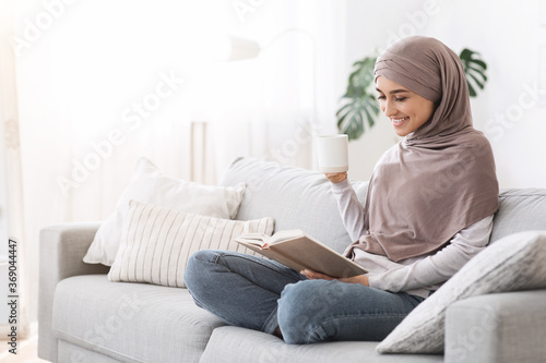 Weekend Pastime. Young Arab Woman Relaxing With Book And Coffee On Couch