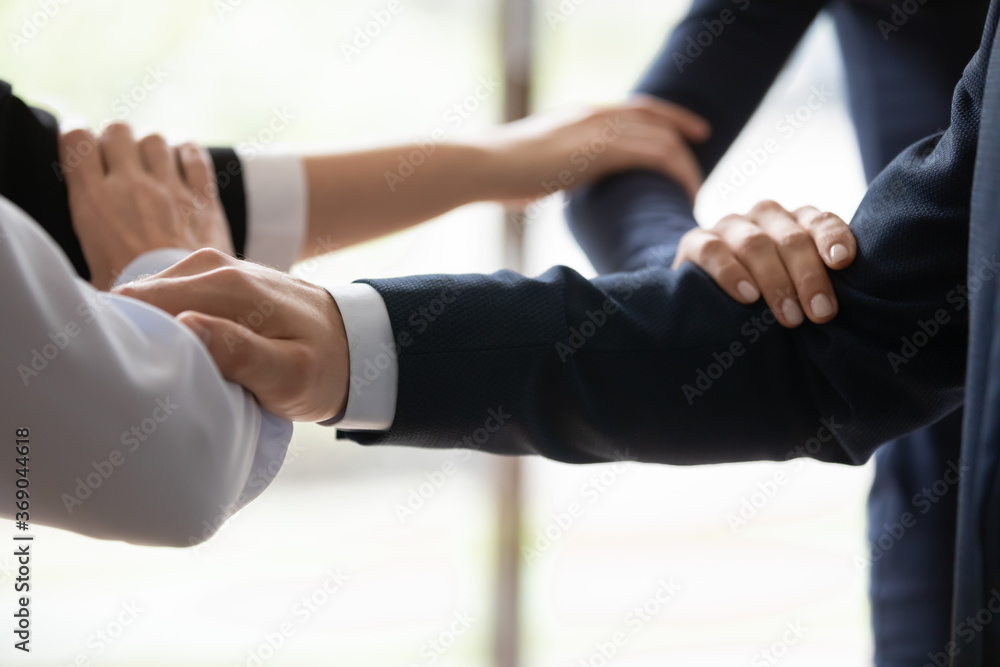 Fototapeta premium Close up businesspeople connected arms standing side by side shoulder by shoulder show business protection, feel unity, corporate spirit save, strength of four, act together towards common aim concept