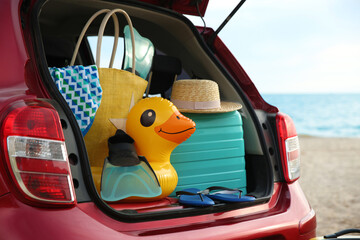 Red car with luggage on beach, closeup. Summer vacation trip