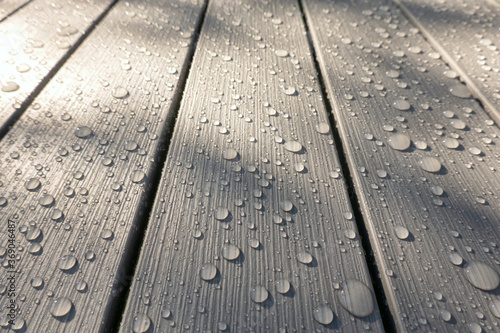 A look at the perspective of gray plastic slats. The surface has an imitation of the wood texture. There are drops of water after the rain. Background. Texture.