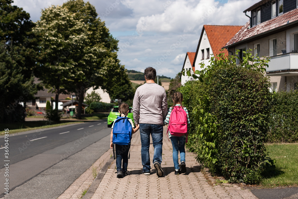 Obraz premium Dad, parent, father leads the children, daughter and son, boy and girl to school. Children go to study after vacation and quarantine. Back to school.