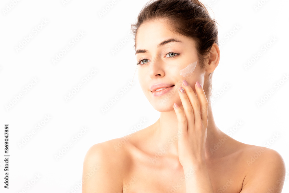Young woman applying cream onto her face Young woman applying cream onto her face