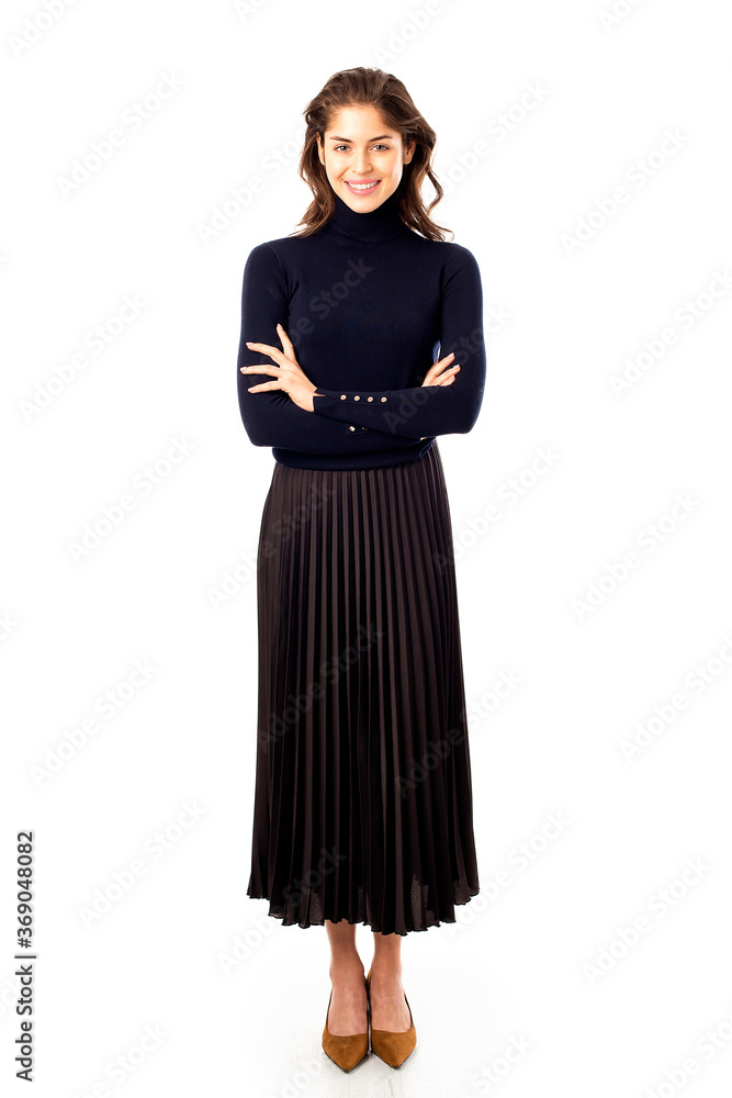 Full length studio shot of happy woman standing with arms crossed at isolated white background