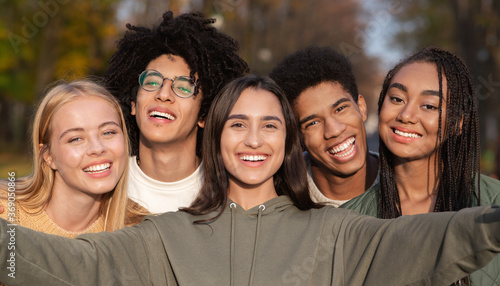 Smiling teen friends taking selfie while walking in park