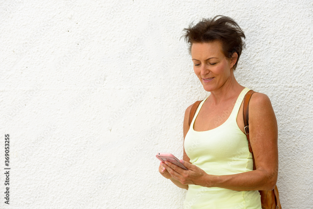 Mature beautiful tourist woman against white wall outdoors Mature beautiful tourist woman against white wall outdoors