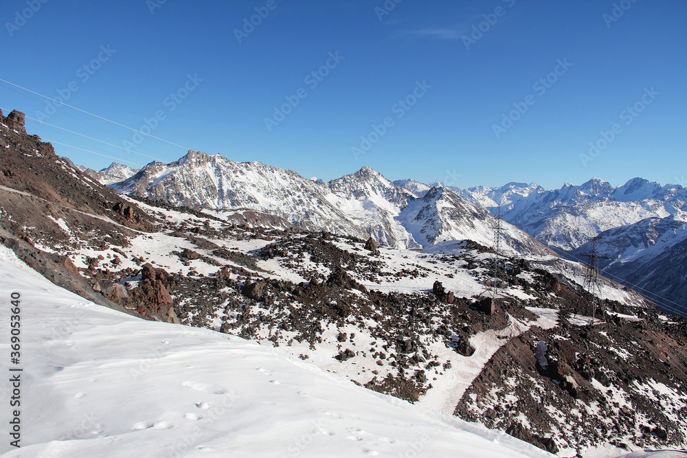 Snow-capped mountain ranges against a bright blue sky. Elbrus