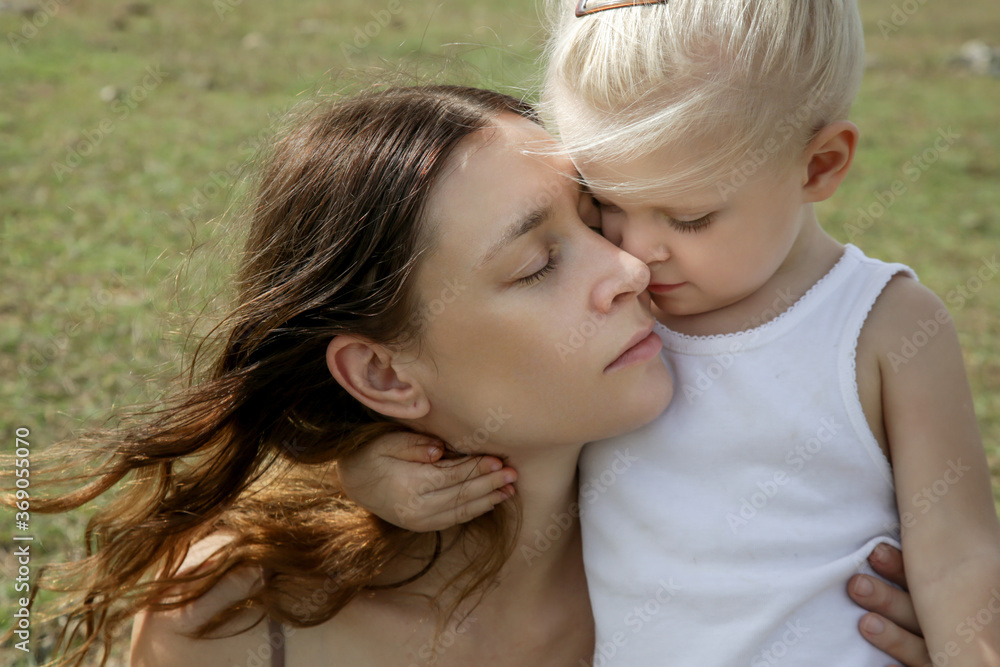 Outdoor candid portrait of mother with her toddler girl. Family time in nature, bonding and affection concept. Outdoor candid portrait of mother with her toddler girl. Family time in nature, bonding and affection concept.
