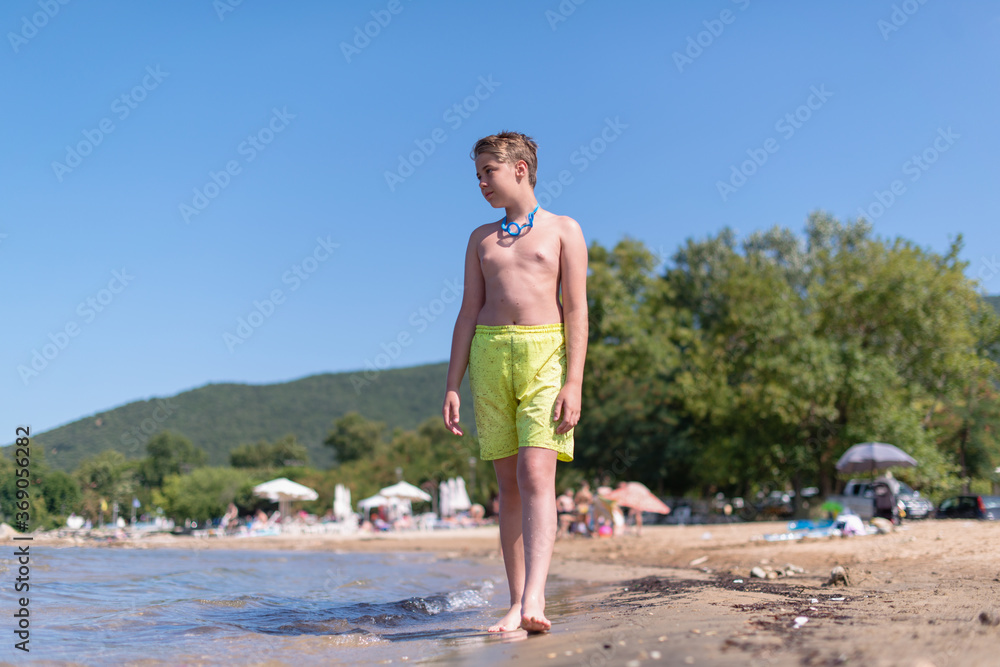Young teenage boy is walking on a beach