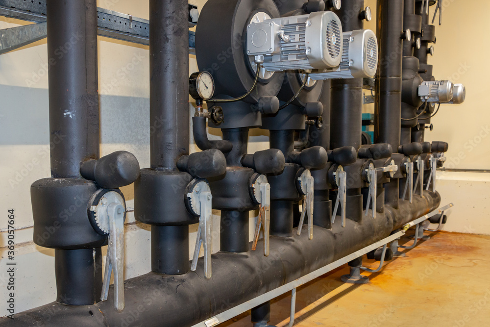 Central heating system in an industrial building, with insulated pipes, manual valves and pumps