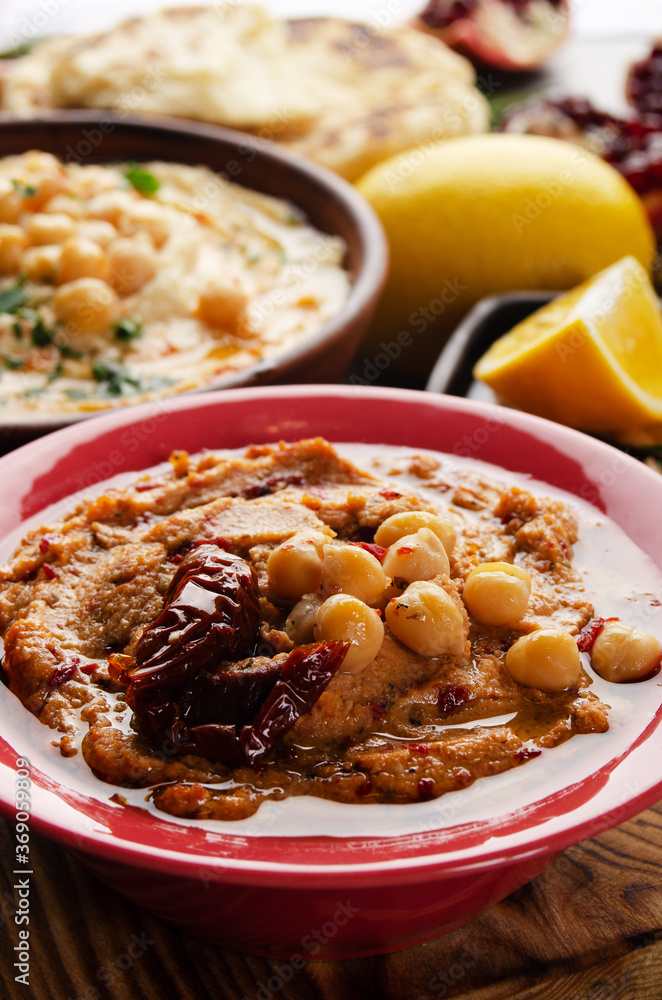 Fresh homemade Hummus in clay dish topped with olive oil, chickpeas, spices and sun dried tomatoes on stone table Fresh homemade Hummus in clay dish topped with olive oil, chickpeas, spices and sun dried tomatoes on stone table