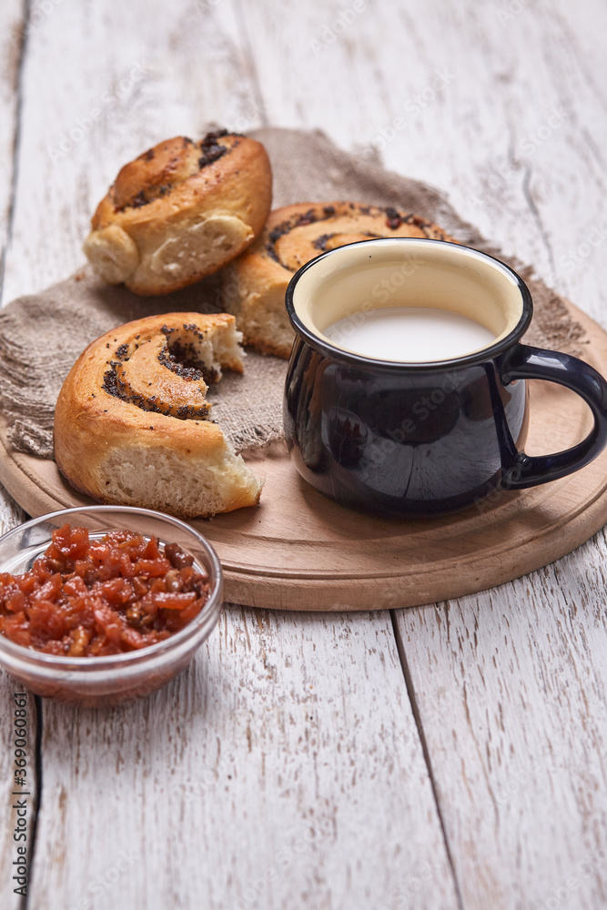 Variety of homemade puff pastry buns cinnamon served with milk cup, jam, butter as breakfast over white plank wooden background. Flat lay, space Variety of homemade puff pastry buns cinnamon served with milk cup, jam, butter as breakfast over white plank wooden background. Flat lay, space