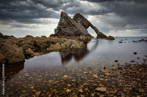 Bow Fiddle Rock on the Moray Coast, Scotland. Dreamy seascape water with leading line of small rocks to the main Big rock.