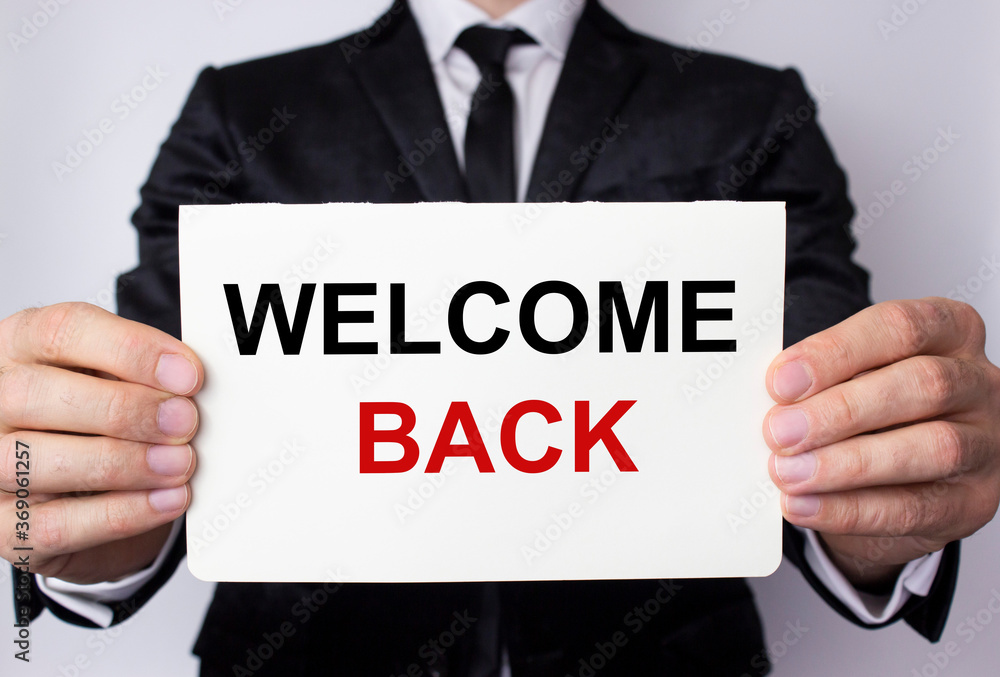 Welcome back inscription on a white sheet of paper in the hands of a businessman on a white background. The concept of returning to the office, school, work, university. Welcome back inscription on a white sheet of paper in the hands of a businessman on a white background. The concept of returning to the office, school, work, university.
