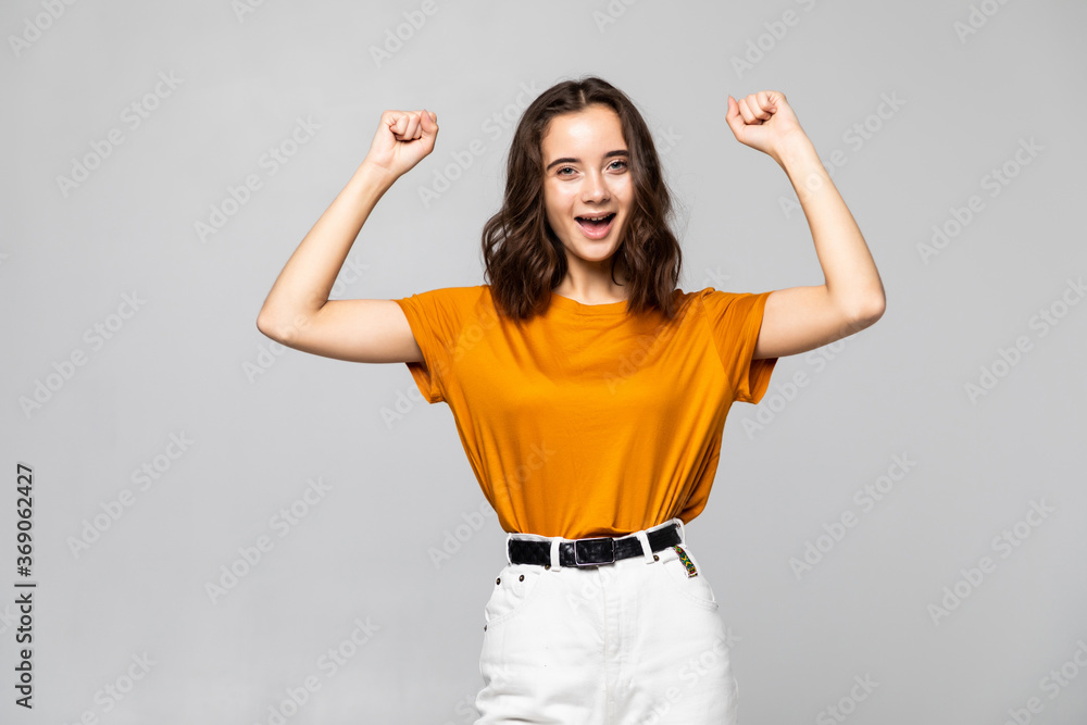 Happy successful young woman shouting and celebrating success isolated over grey background Happy successful young woman shouting and celebrating success isolated over grey background