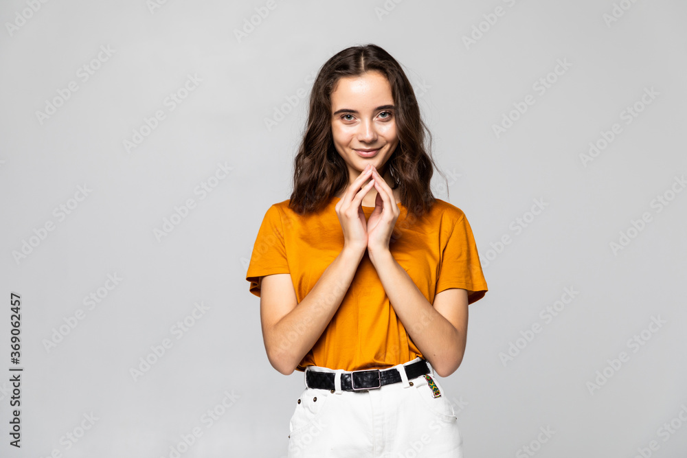 pretty young excited woman with her hands under chin against grey background pretty young excited woman with her hands under chin against grey background