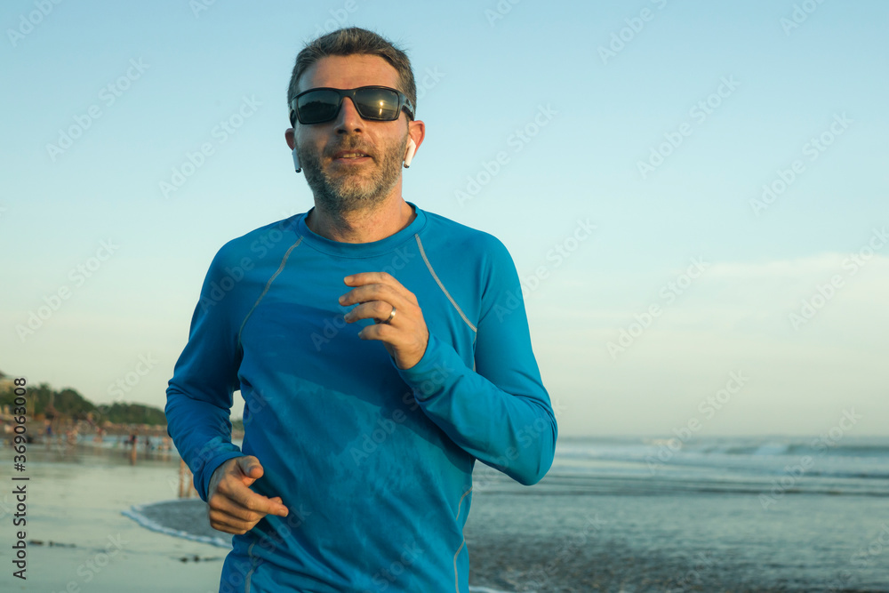 outdoors running workout - young attractive and athletic runner man jogging on beautiful beach in Summer training happy and free in fitness and healthy lifestyle concept outdoors running workout - young attractive and athletic runner man jogging on beautiful beach in Summer training happy and free in fitness and healthy lifestyle concept