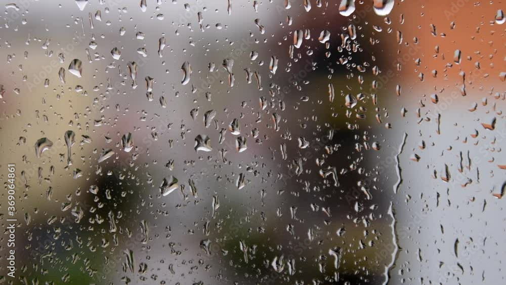 Rain drops falling on the window. Blurred residential area in background. Rain drops falling on the window. Blurred residential area in background.