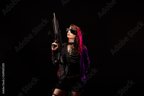 Young woman dressed in a studded leather jacket, a pair of cyberpunk glasses, holding an assault rifle in her hands © Warpedgalerie