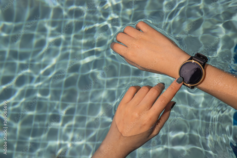 Close up of female using hands with the smart watch at the pool. Healthy lifestyle concept.