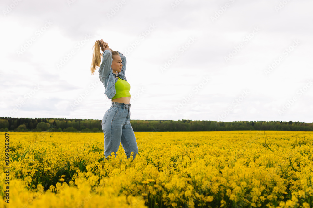 a blonde girl walks in a rapeseed field in the summer a blonde girl walks in a rapeseed field in the summer