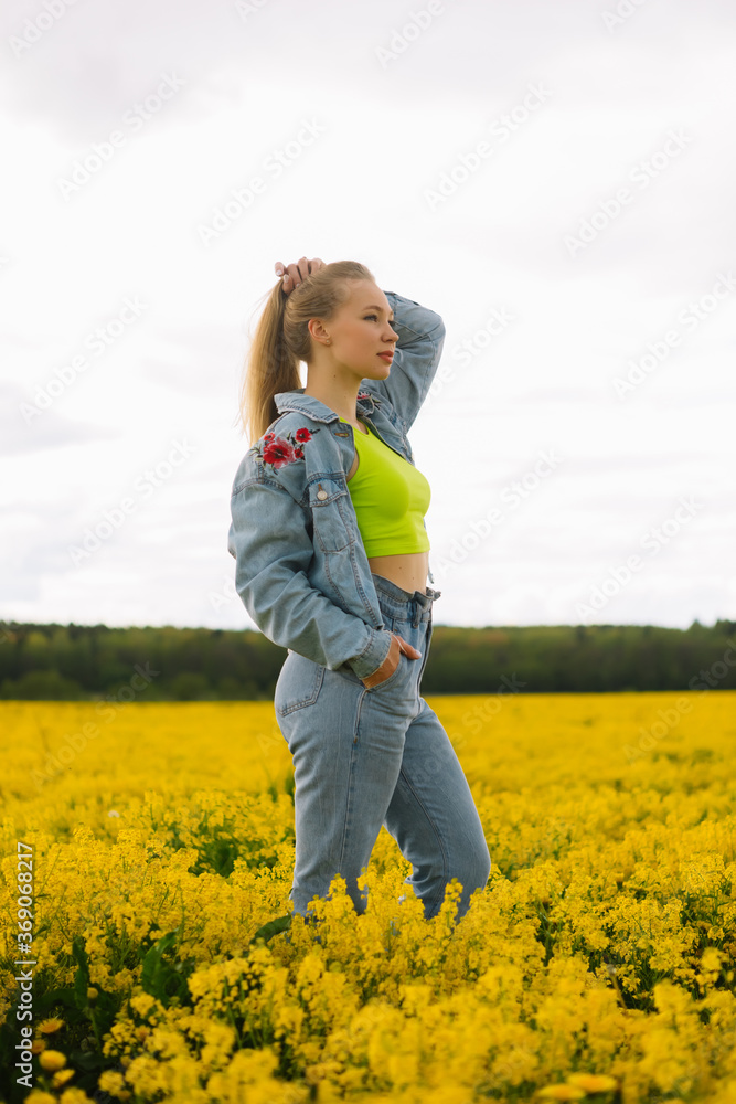 a blonde girl walks in a rapeseed field in the summer a blonde girl walks in a rapeseed field in the summer