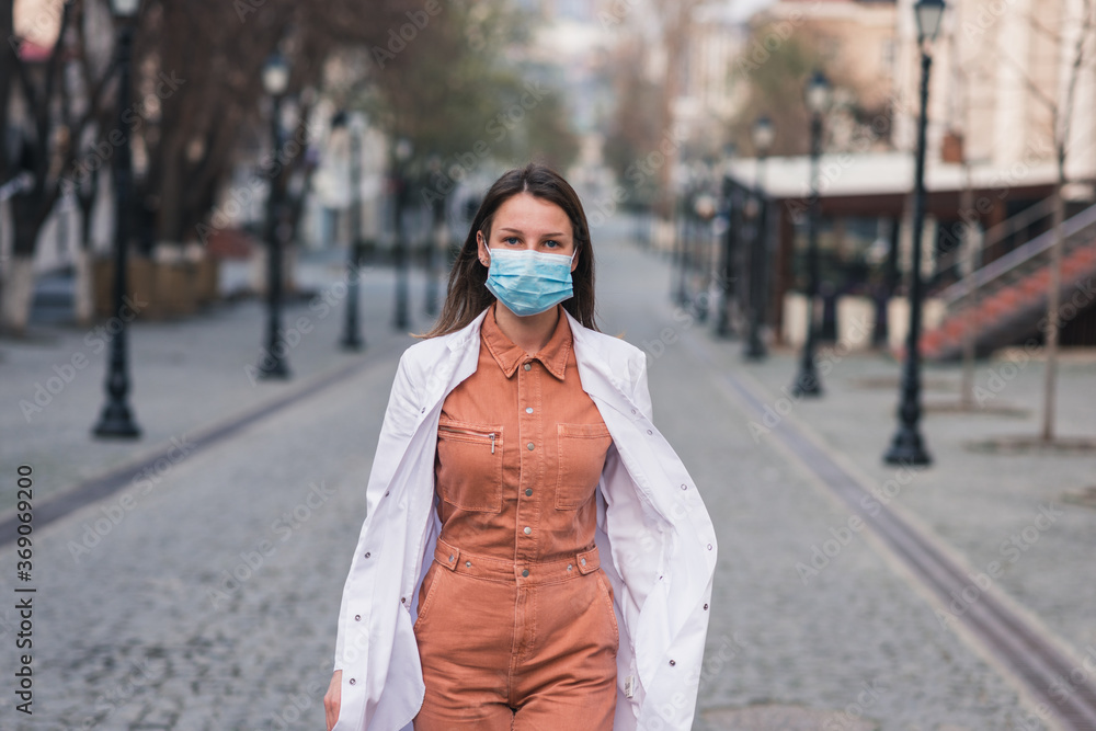 a brunette woman in orange clothes wearing white medical coat and a protective mask on her face a brunette woman in orange clothes wearing white medical coat and a protective mask on her face
