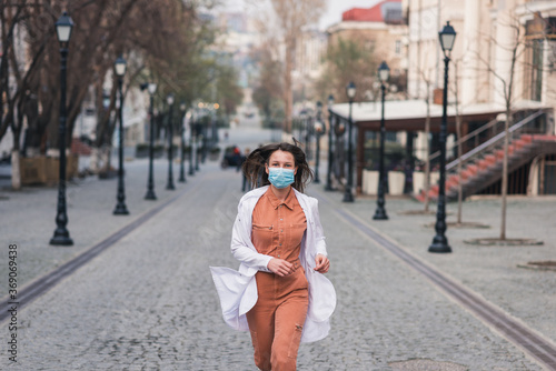 a brunette woman in orange clothes wearing white medical coat and a protective mask on her face