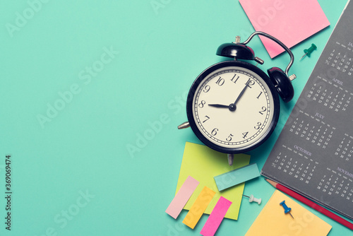 close up of alarm clock and calendar on the green table background, planning for business meeting or travel planning concept