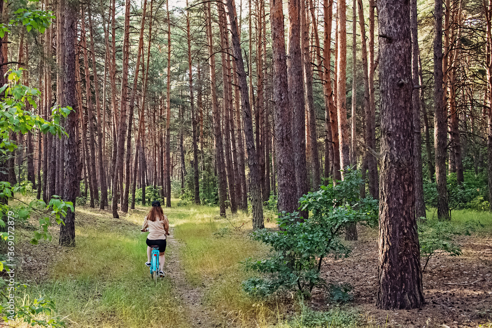 Young woman riding a bike in pine forest