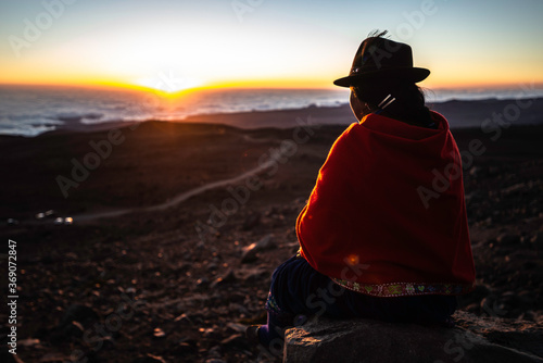 Фотография Chimborazo providence at Chimborazo volcano, Ecuador 21/sep/2013 a young indigenous, resting on a rock waiting to the sun to set over the clouds