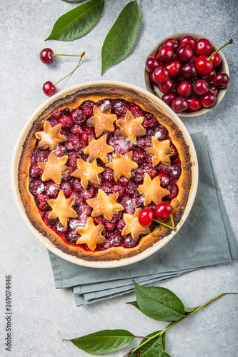 Homemade open cherry pie with frech cherries on a gray concrete background.