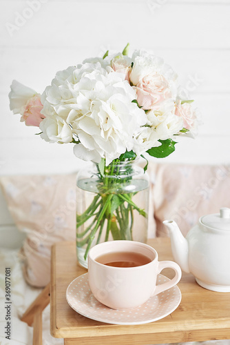 Breakfast in bed in hotel room. Accommodation. Breakfast in bed with tea cup and flowers on bed background top view. Copy Space. Romantic valentine's day breakfast. Cozy morning. Happy Mother's Day
