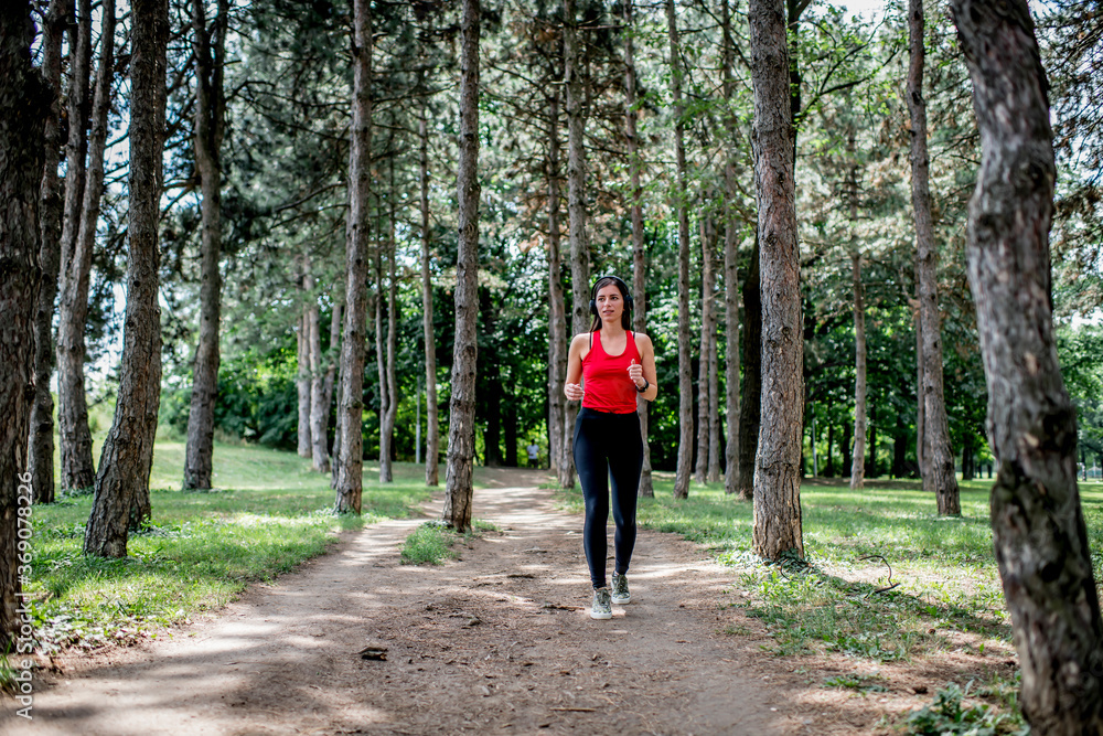 Young sporty woman jogging through the forest
