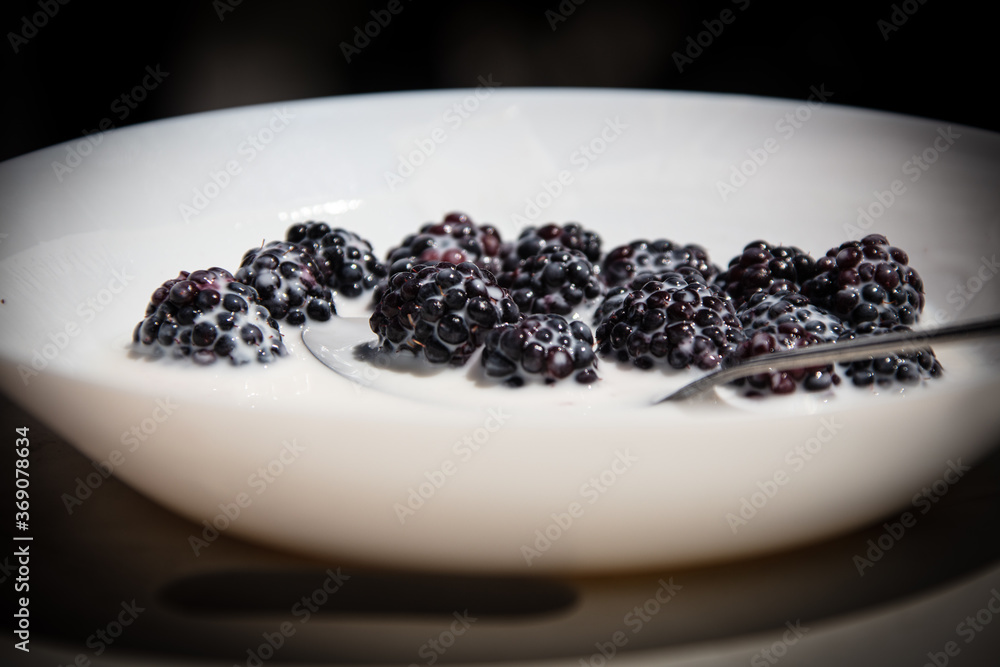 blackberries in the yoghurt in a white plate