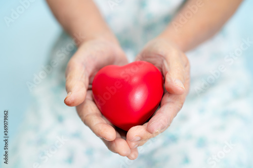 Asian senior or elderly old lady woman patient holding red heart in her hand on bed in nursing hospital ward  healthy strong medical concept