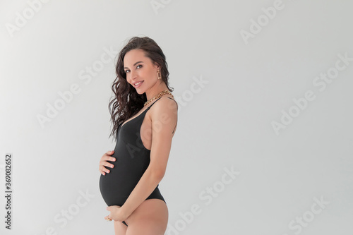 glamorous Pregnant in a black bodiesuit. Portrait of young pregnant beautiful brunette